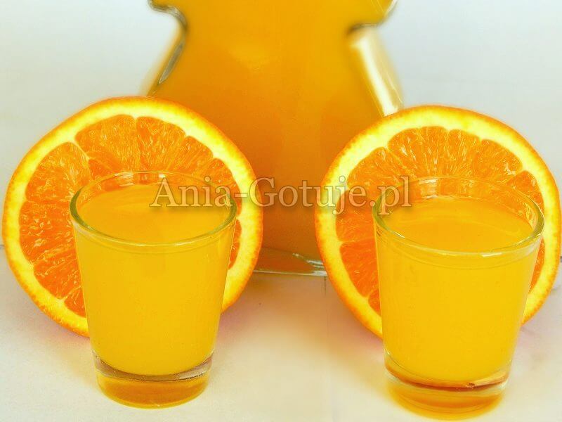 na zdjęciu likier z pomarańczy w tle pomarańcze i butelka